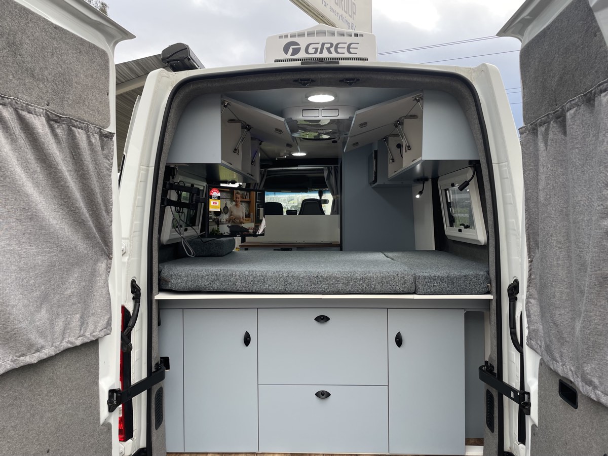 Campervan kitchen with fridge, microwave and cabinetry fitted by Focus RV